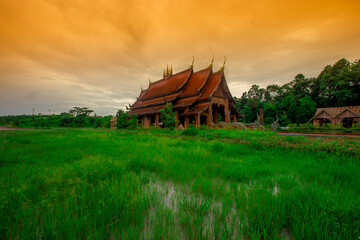 The background of the Wat Pa Kham Charoen is a beautiful old church with a Buddhist statue and a tree-lined temple, with tourists and travelers always making merit in Udon Thani, Thailand.