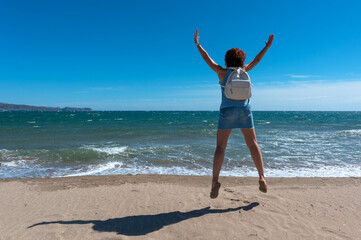 Woman jumping for joy on a beach on a sunny day