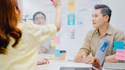 Asia businesspeople discussing business brainstorm meeting together share data and write on acrylic...