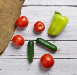 still life with tomatoes, cucumbers, pepper on an old wooden light rustic table with an old bag