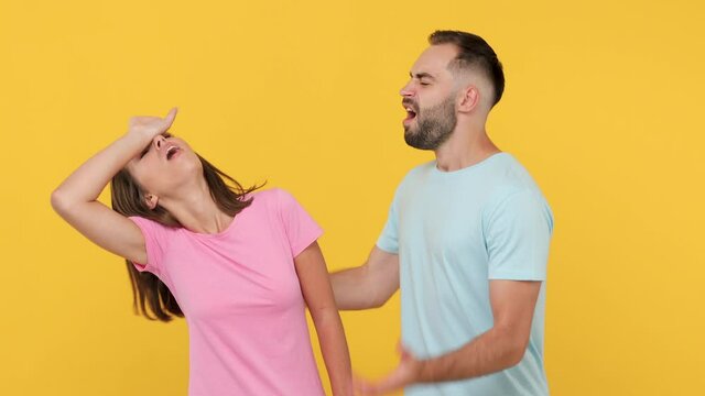 Young actors couple man woman in basic t-shirts posing isolated on yellow background studio. Start to play emotion like movie theater after clapperboard closing gesture fooling around fainting begging