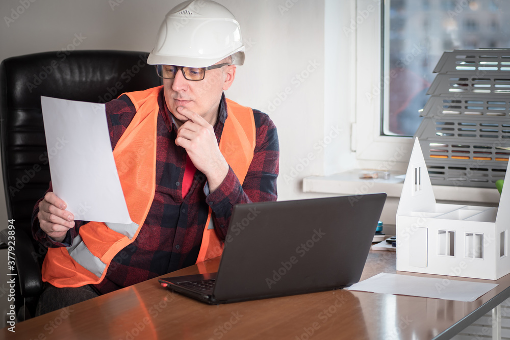 Poster work in a construction company. work on the project of a new house. the engineer studies the documen