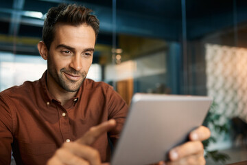 Fototapeta na wymiar Smiling businessman using a tablet at his office desk