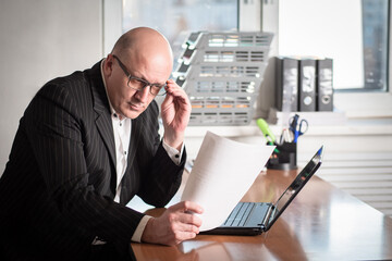 The man with glasses looks at the paper document in amazement. Unexpected business proposal. A...
