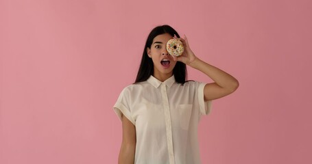 Elated woman having fun peeking through glazed donuts