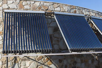 Solar water heating system installed on wall or roof of house. 3 panels of glass coaxial tubes with water to accumulate heat. Side view. Concept environmentally friendly and economical home heating © AllUneed