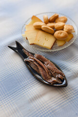 Vertical shot of anchovies caught in the Cantabrian Sea plated in a blue fish shaped plate served with cheese on a blue squared tablecloth. Anchovy is a typical tapas dish from the northern Spain.