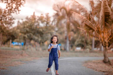 Blurred abstract background of Asian girls, cute in a bright dress, playing on the street or in a park, when parents watch closely.