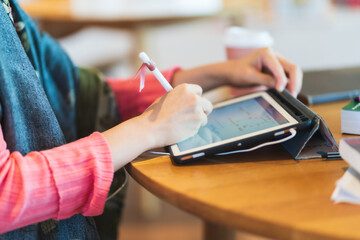 Close up hand of Asian woman in pink sweater use tablet for e-learning
