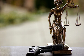 Closeup of the Lady Justice statue with a gun under the lights against a blurry background