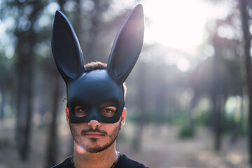 Chico joven con mascara de conejo negro en un bosque