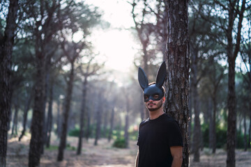 Chico joven con mascara de conejo negro en un bosque