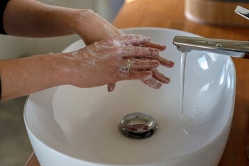 Woman washing hands with soap and running warm water over the sink. Coronavirus prevention concept.