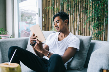 Young man checking notebook sitting on sofa