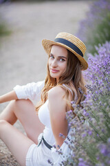 Beautiful young woman in the sunset light. Portrait of a beautiful woman in blooming lavender. Summer.