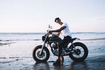 Fototapeta na wymiar Young male sitting on motorcycle on beach