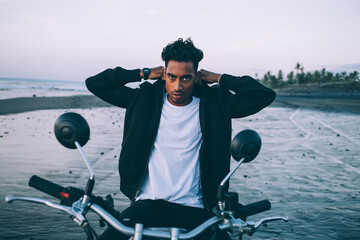 Biker adjusting bomber jacket on seashore