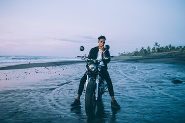Ethnic man on motorbike smoking on seaside