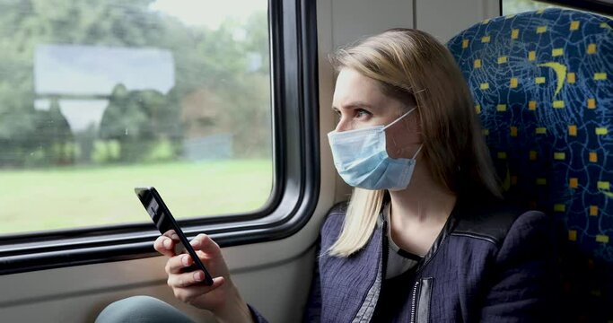 young woman with face mask using mobile phone in train. safety in public transport