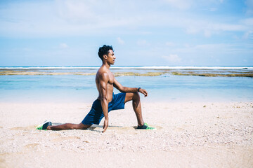 Fototapeta na wymiar Hispanic sportsman doing exercises on sandy beach