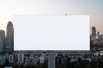 Blank white road billboard with Bangkok cityscape background at sunset. Street advertising poster, mock up, 3D rendering. Front view. The concept of marketing communication to promote or sell idea.