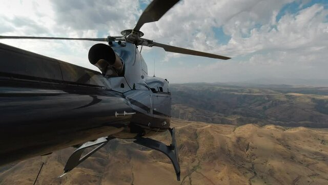 A US Army helicopter flies over the mountains in Afghanistan. View from the tail of the helicopter in 4K