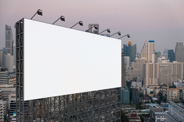 Blank white road billboard with Bangkok cityscape background at sunset. Street advertising poster, mock up, 3D rendering. Side view. The concept of marketing communication to promote or sell idea.