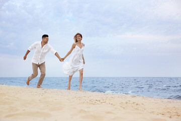 Fototapeta na wymiar Happy couple running on beach, space for text. Romantic walk