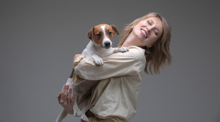 Pretty woman holds her puppy in front of face