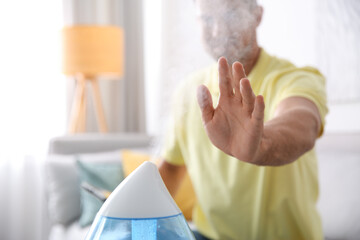Man near modern air humidifier at home, closeup