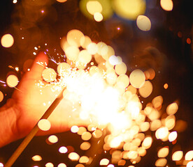 Sparks and light from sparklers in the dark on the palm of a person. Christmas magic, new year's...
