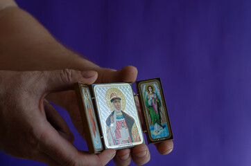 Hands hold the Christian icon of the sacred princess Olga and the archangels Gabriel and Michael.