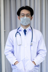 Portrait of Asian doctor man wearing stethoscope white coat standing in modern hospital.