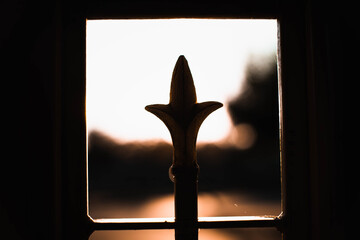 Closeup of the sunset through a patterned gate on blurred background