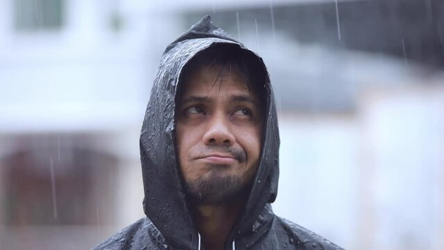 close up young man wearing a raincoat in the rain slow motion