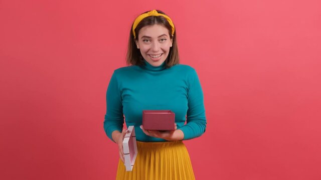 Portrait of happy woman opening gift box against red background.