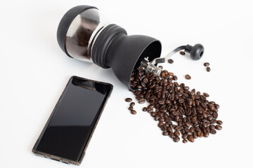 coffee grinder with coffee beans and black screen mobile phone on white background