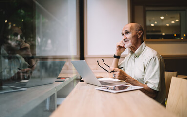 Thoughtful businessman working remotely on laptop and looking away