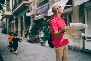 Thoughtful male tourist with paper map on street