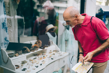 Focused beard senior man during window shopping