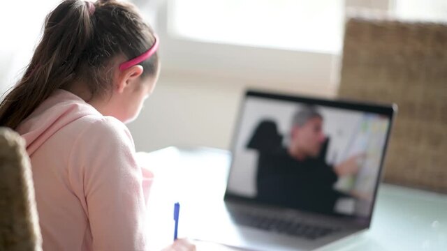 School from home concept. Teacher explaining lesson to young girl in primary school following from laptop screen