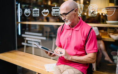 Focused man browsing tablet on street near coffee shop