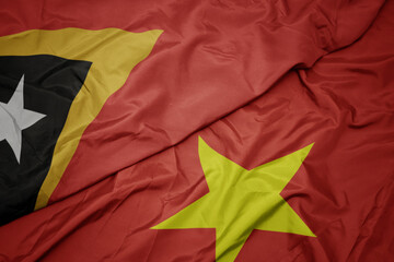 waving colorful flag of vietnam and national flag of east timor.