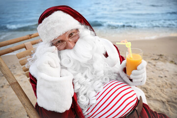 Obraz premium Santa Claus with cocktail relaxing on beach. Christmas vacation
