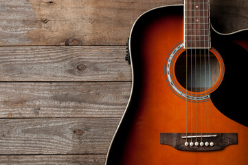 Naklejka premium A black and orange acoustic guitar on wooden floor