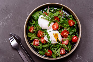 Cherry Tomatoes, poached eggs and herbs mix salad on dark background. Simple and healthy nutrition. Selective focus