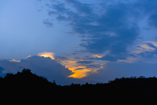 A photograph of  Iridescent Pileus Cloud in the twilight colored sky in the evening. The bellow edge of the image is a black large mountain. Feeling calm and relax. There is a copy space on top..