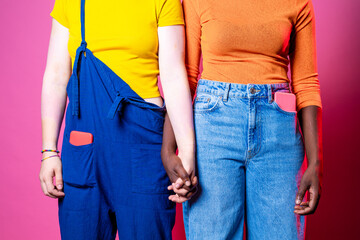 Midsection of young women holding hands standing indoors