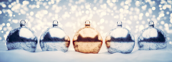 Shiny Christmas balls on snow, glitter lights background