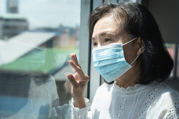 Asian old woman in surgical mask looking outdoor.